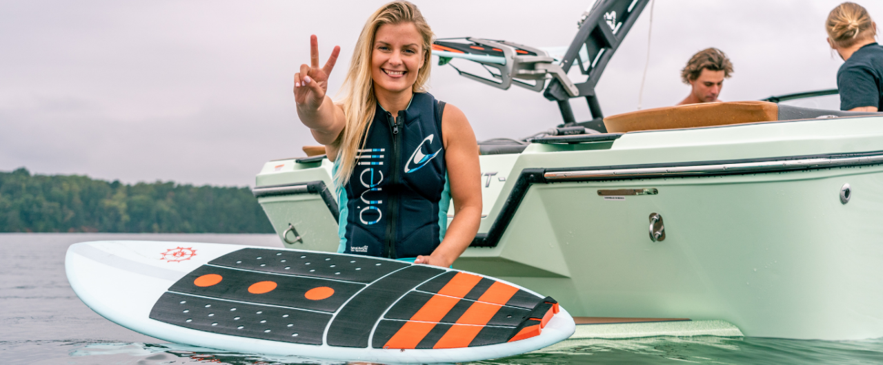 woman giving the peace sign holding a surf board